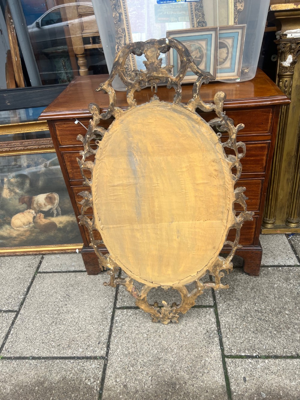 An 18th-century style oval wall mirror featuring a carved giltwood frame with openwork scrollwork and acanthus leaf cresting. View XIV