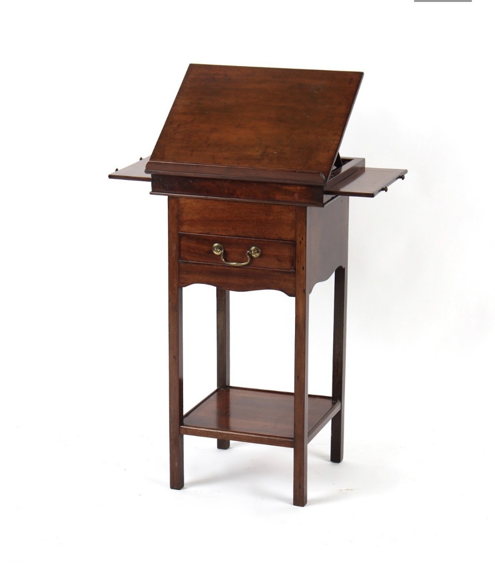 A tall Georgian mahogany artist table featuring an adjustable tilted writing surface, extendable side slides, a drawer with a brass handle, and a lower shelf.