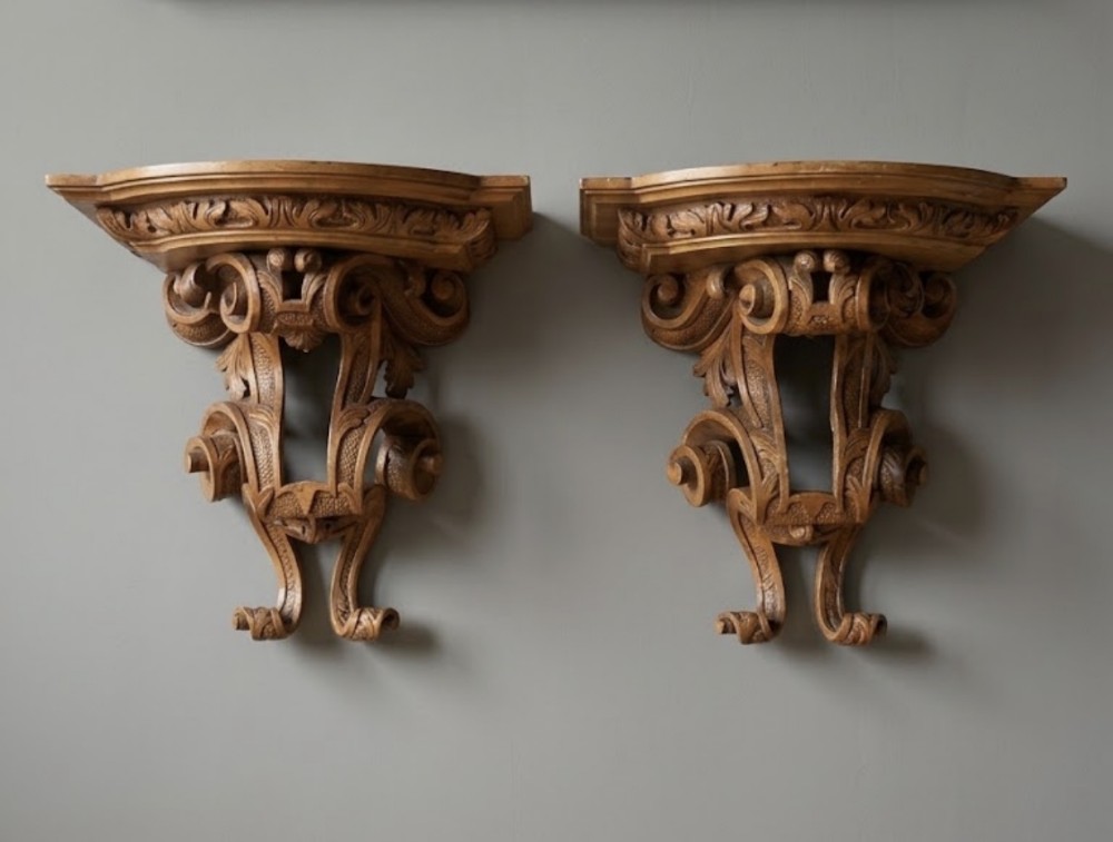 A pair of Georgian carved walnut wall brackets featuring scrollwork and acanthus leaf details mounted against a plain wall.