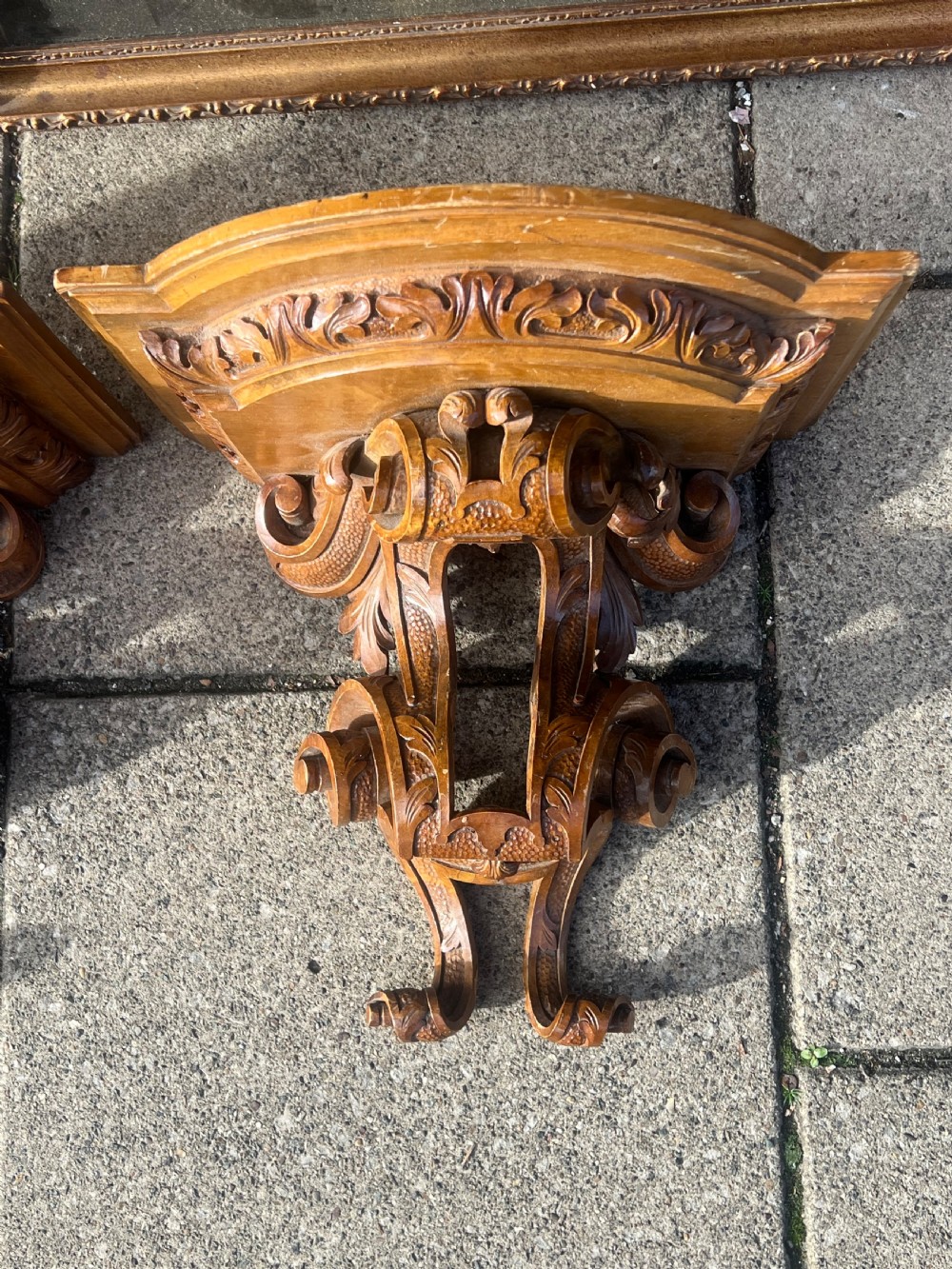 A pair of Georgian carved walnut wall brackets featuring scrollwork and acanthus leaf details mounted against a plain wall. View V