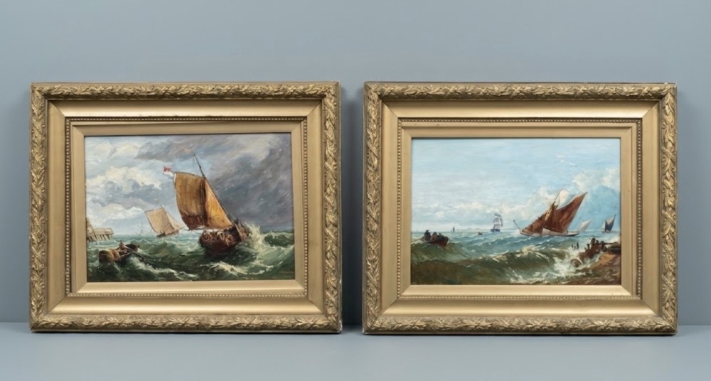 A pair of antique seascape oil paintings depicting sailing ships on choppy ocean waves, housed in matching gilt gesso frames.