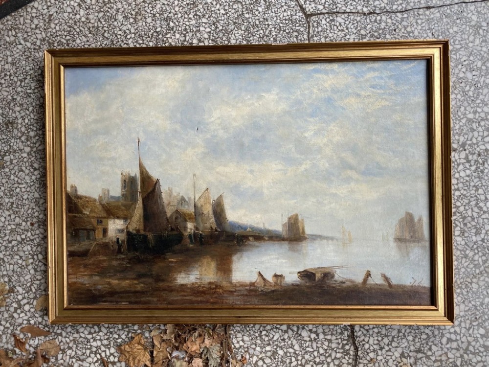 A large framed oil painting depicting sailing boats moored along a harbour shore with coastal buildings under a pale cloudy sky. View II