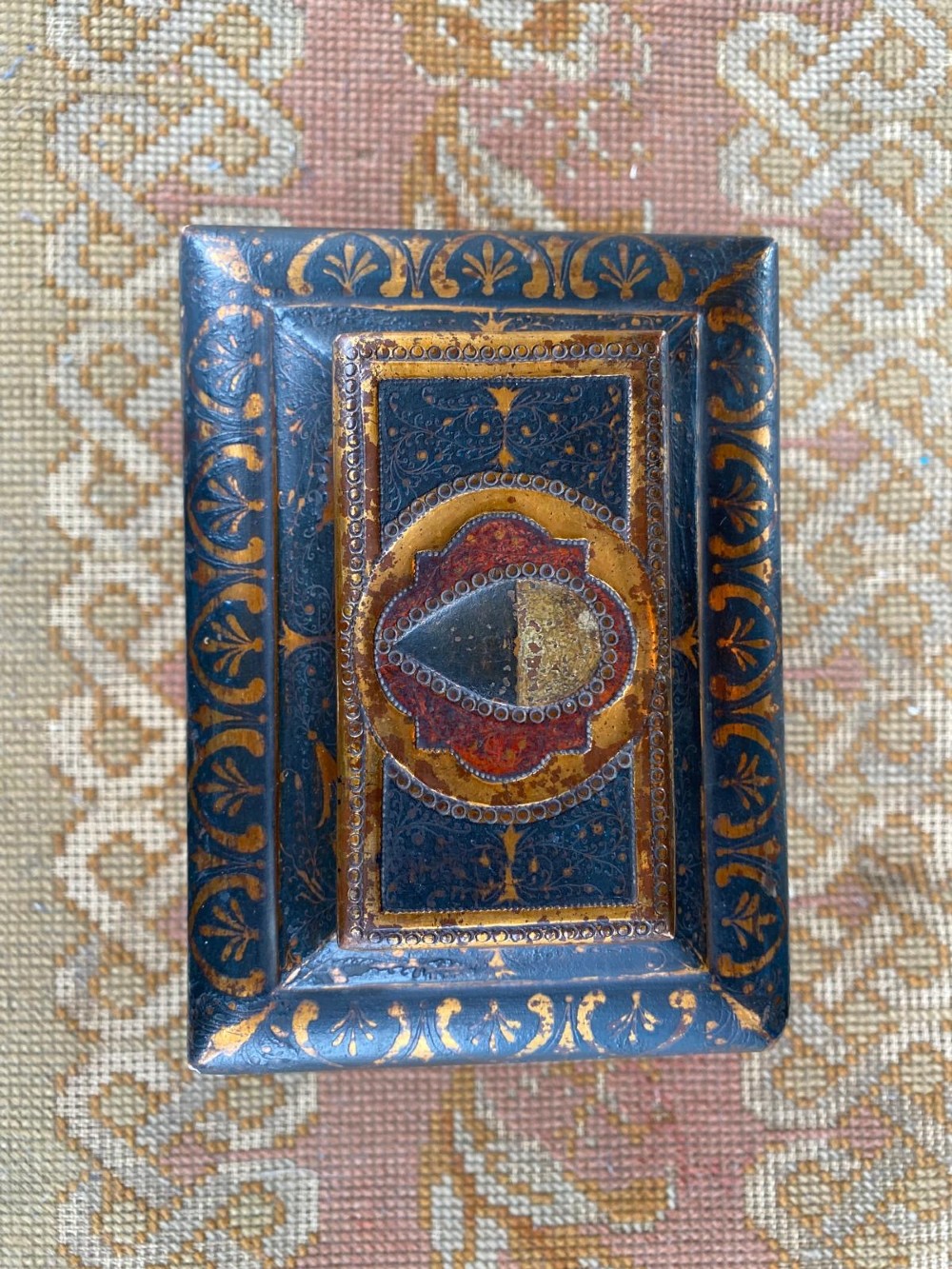 A small rectangular wooden casket featuring a painted medieval figure scene on the front, a gilded stepped lid, and black ball feet. View II