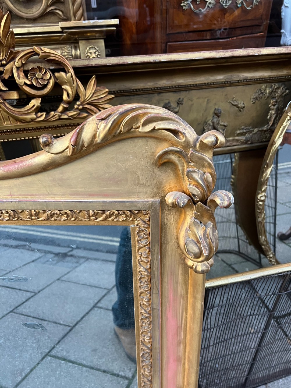 An ornate antique giltwood overmantel mirror featuring a carved acanthus leaf cresting and a decorative beaded inner frame. View V