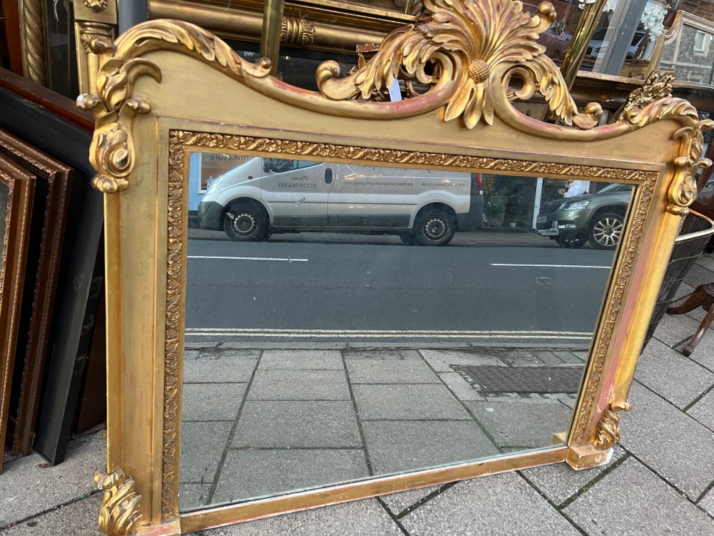An ornate antique giltwood overmantel mirror featuring a carved acanthus leaf cresting and a decorative beaded inner frame. View VIII