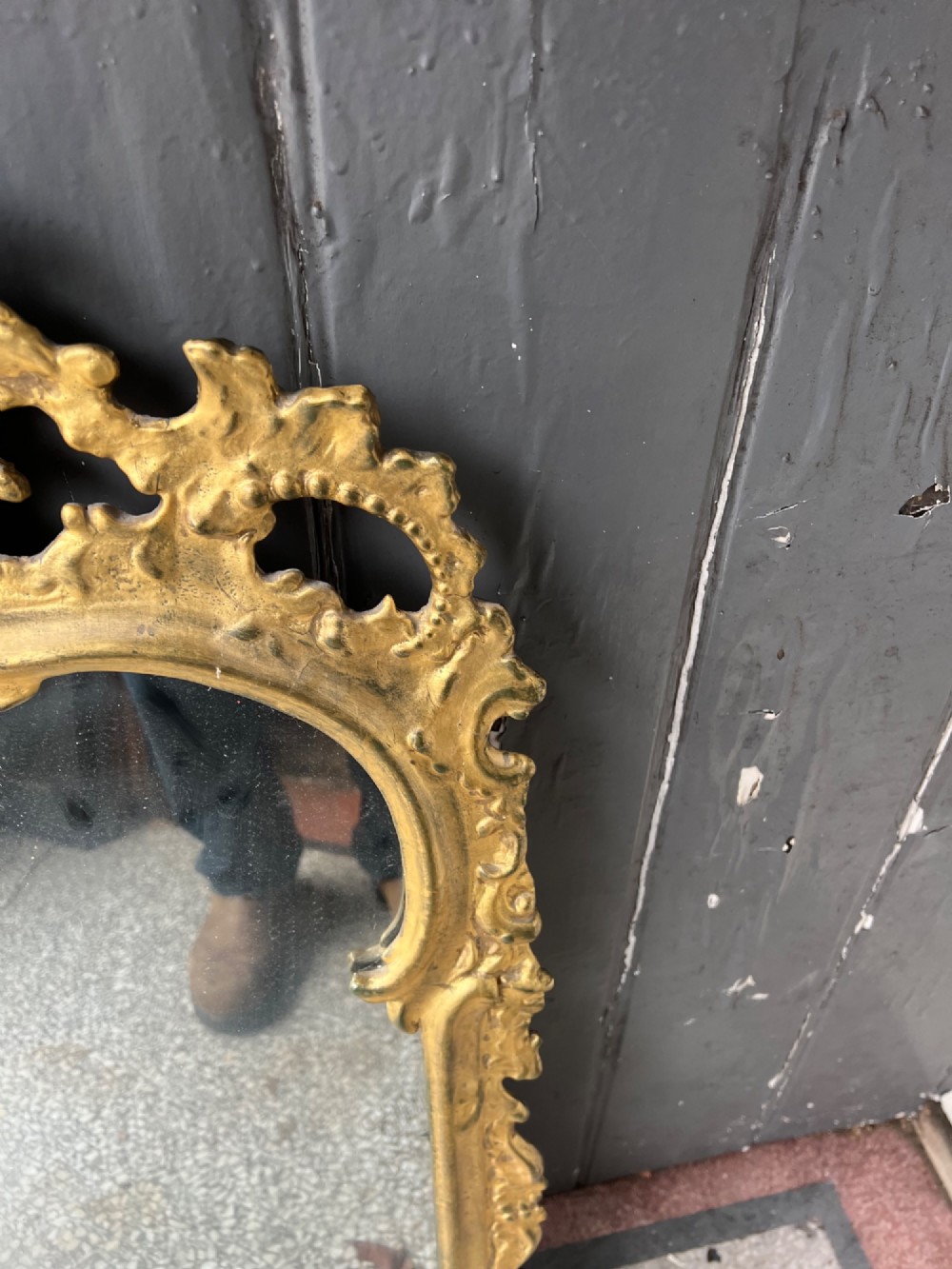 An 18th-century style wall mirror featuring an ornate carved gold giltwood frame with pierced cresting and acanthus leaf detail surrounding a shaped glass pane. View V