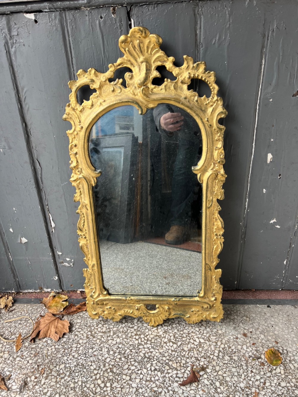 An 18th-century style wall mirror featuring an ornate carved gold giltwood frame with pierced cresting and acanthus leaf detail surrounding a shaped glass pane. View VII
