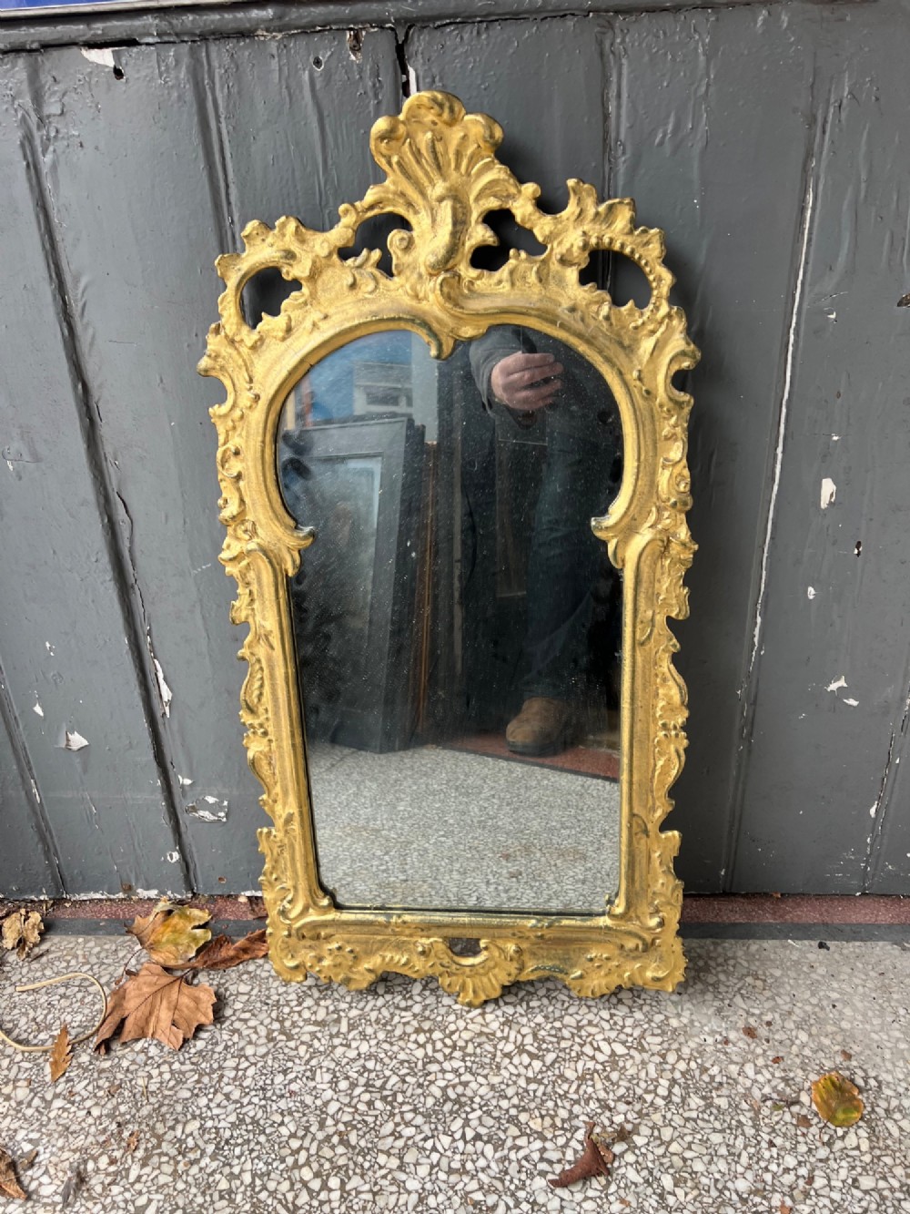 An 18th-century style wall mirror featuring an ornate carved gold giltwood frame with pierced cresting and acanthus leaf detail surrounding a shaped glass pane. View VIII