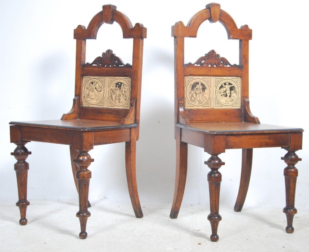Pair of oak hall chairs with with Shakespeare tiles inset.