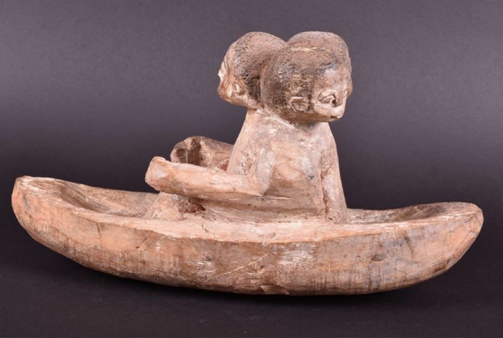 An Early 20th century or earlier African wooden study of a three headed figure seated on a boat