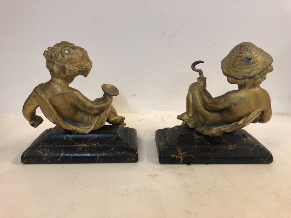 Pair of gilt metal cherub ornaments on marble bases View V