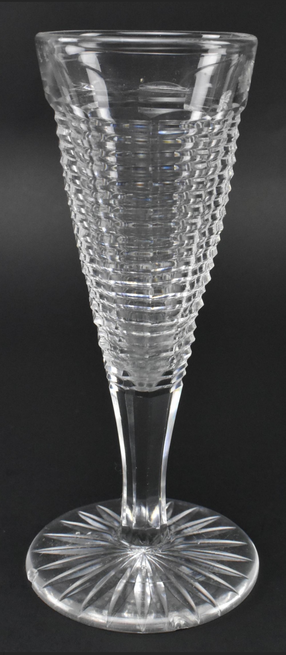 A clear Georgian lead crystal flute glass featuring a diamond-cut bowl, a faceted stem, and a star-cut circular foot.