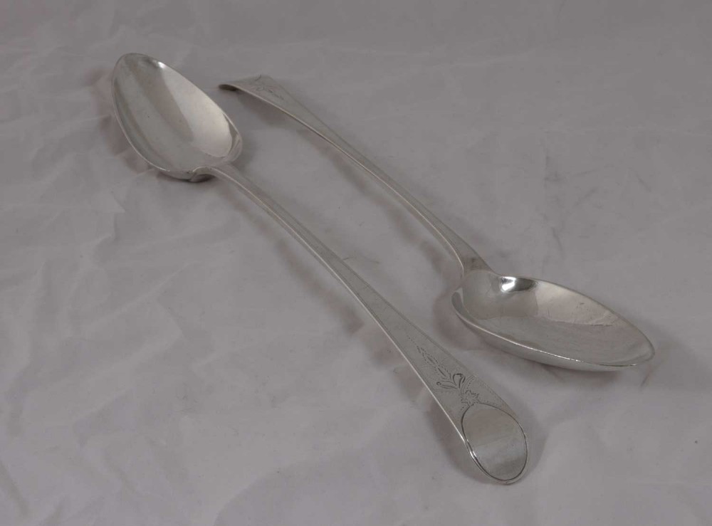 A pair of George III sterling silver serving spoons featuring the Old English pattern with engraved terminals.
