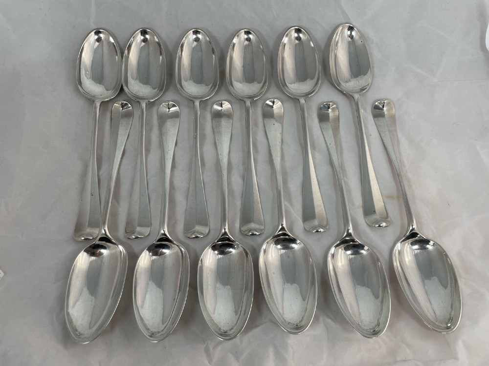 A set of twelve polished Scottish sterling silver table spoons arranged in two rows on a plain background.