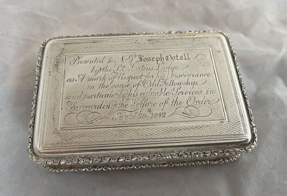 An early Victorian silver rectangular presentation snuff box featuring detailed hand-engraved cursive script dated 1842 and floral repousse borders.