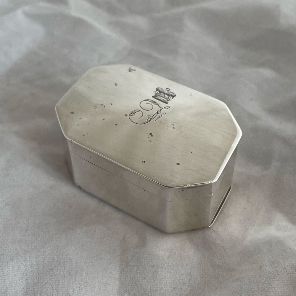 An octagonal Georgian sterling silver nutmeg grater box featuring an engraved crest and hinged lid.