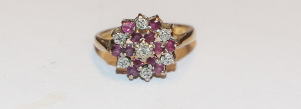 A 9ct yellow gold ring featuring a central diamond surrounded by a flower-shaped cluster of deep red garnets and smaller accent diamonds.