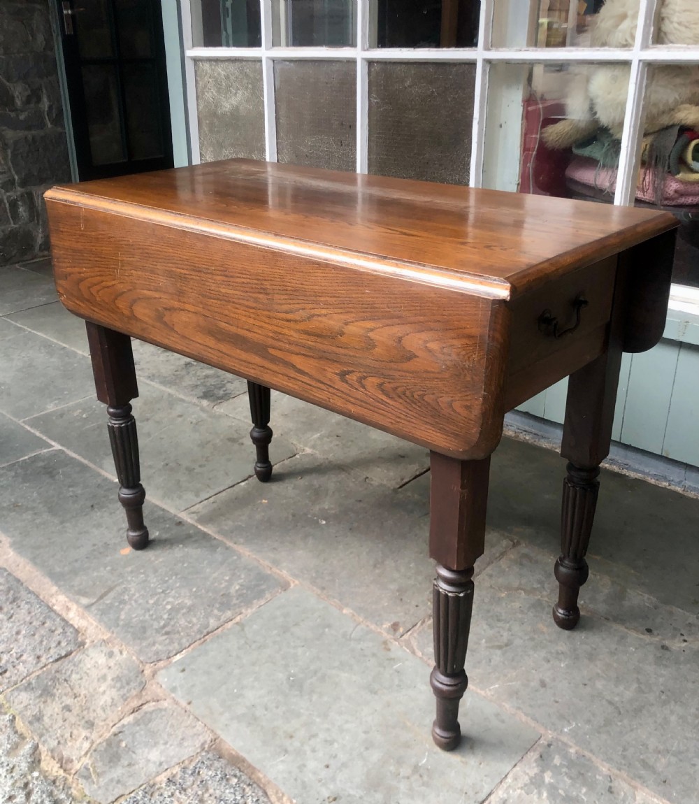 An antique oak chapel table featuring a rectangular drop-leaf top, a single end drawer with a metal handle, and dark turned reeded legs.