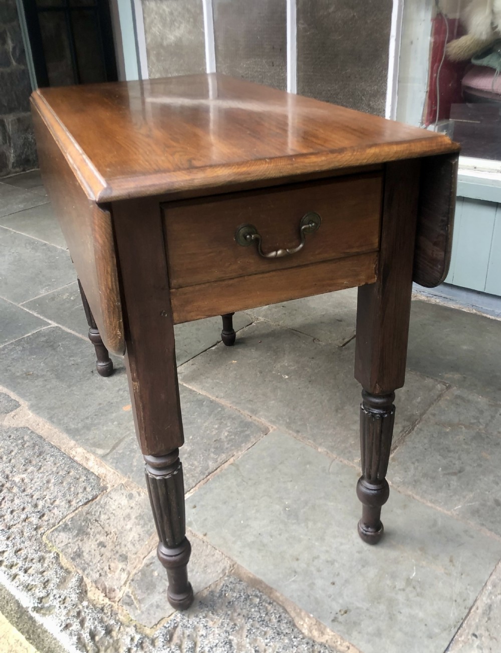 An antique oak chapel table featuring a rectangular drop-leaf top, a single end drawer with a metal handle, and dark turned reeded legs. View III