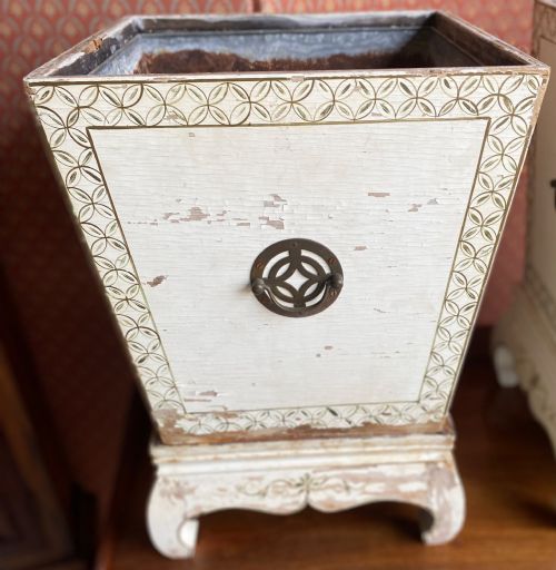 fig 1. A pair of square cream painted wooden planters featuring raised figural motifs and banana palm tree designs on stepped bases with removable metal liners.