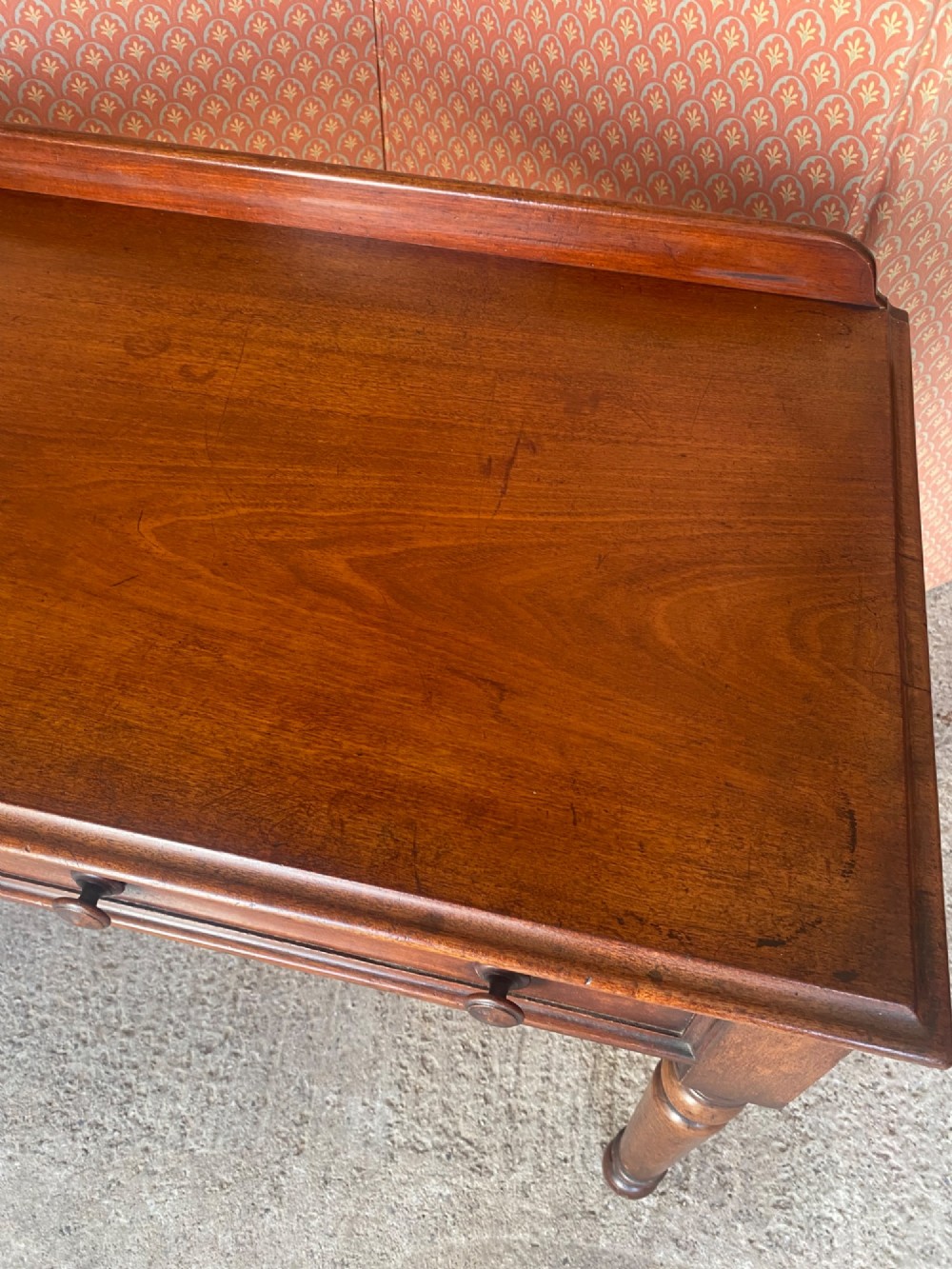 A Victorian mahogany writing table featuring a low gallery upstand, two drawer fronts with turned wooden knobs, and four turned legs. View II
