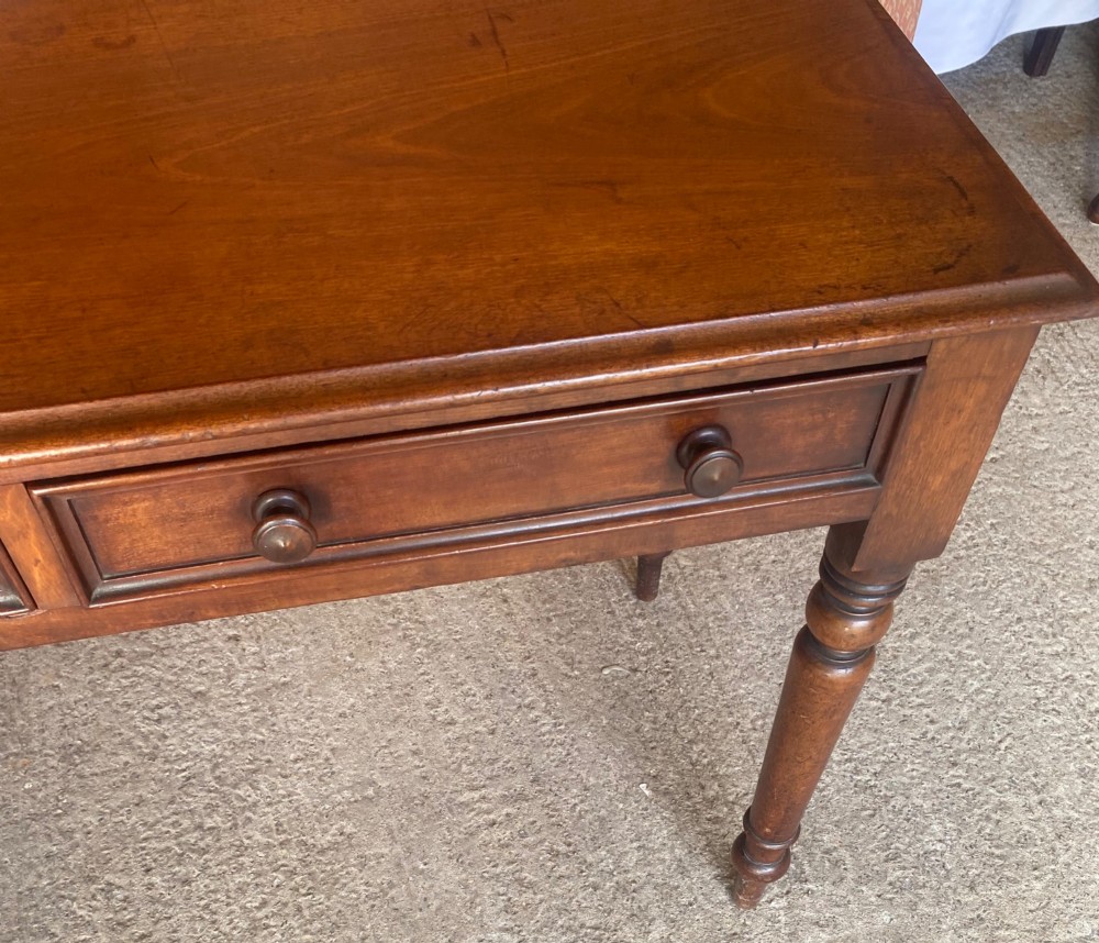 A Victorian mahogany writing table featuring a low gallery upstand, two drawer fronts with turned wooden knobs, and four turned legs. View III