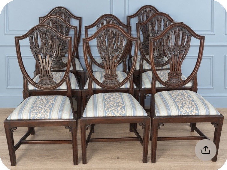 Set of eight mahogany Regency dining chairs featuring openwork carved shield backs and patterned upholstered seats.