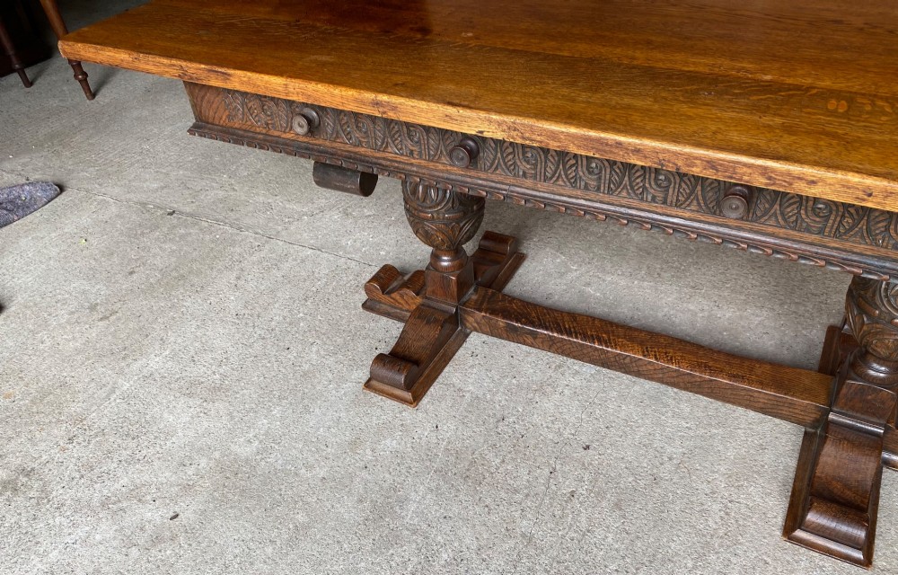 A rectangular solid oak refectory dining table featuring a carved frieze, carved bulbous turned legs, and a low stretcher base. View IV
