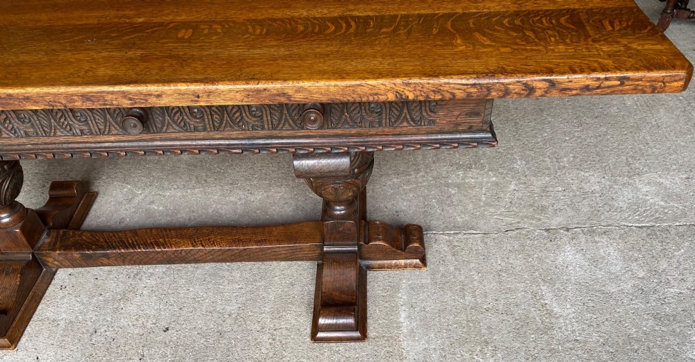 A rectangular solid oak refectory dining table featuring a carved frieze, carved bulbous turned legs, and a low stretcher base. View V