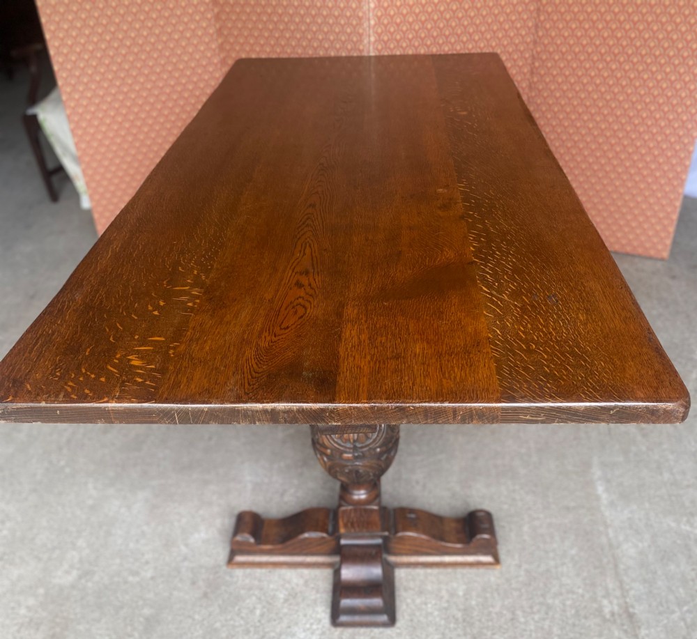 A rectangular solid oak refectory dining table featuring a carved frieze, carved bulbous turned legs, and a low stretcher base. View IX
