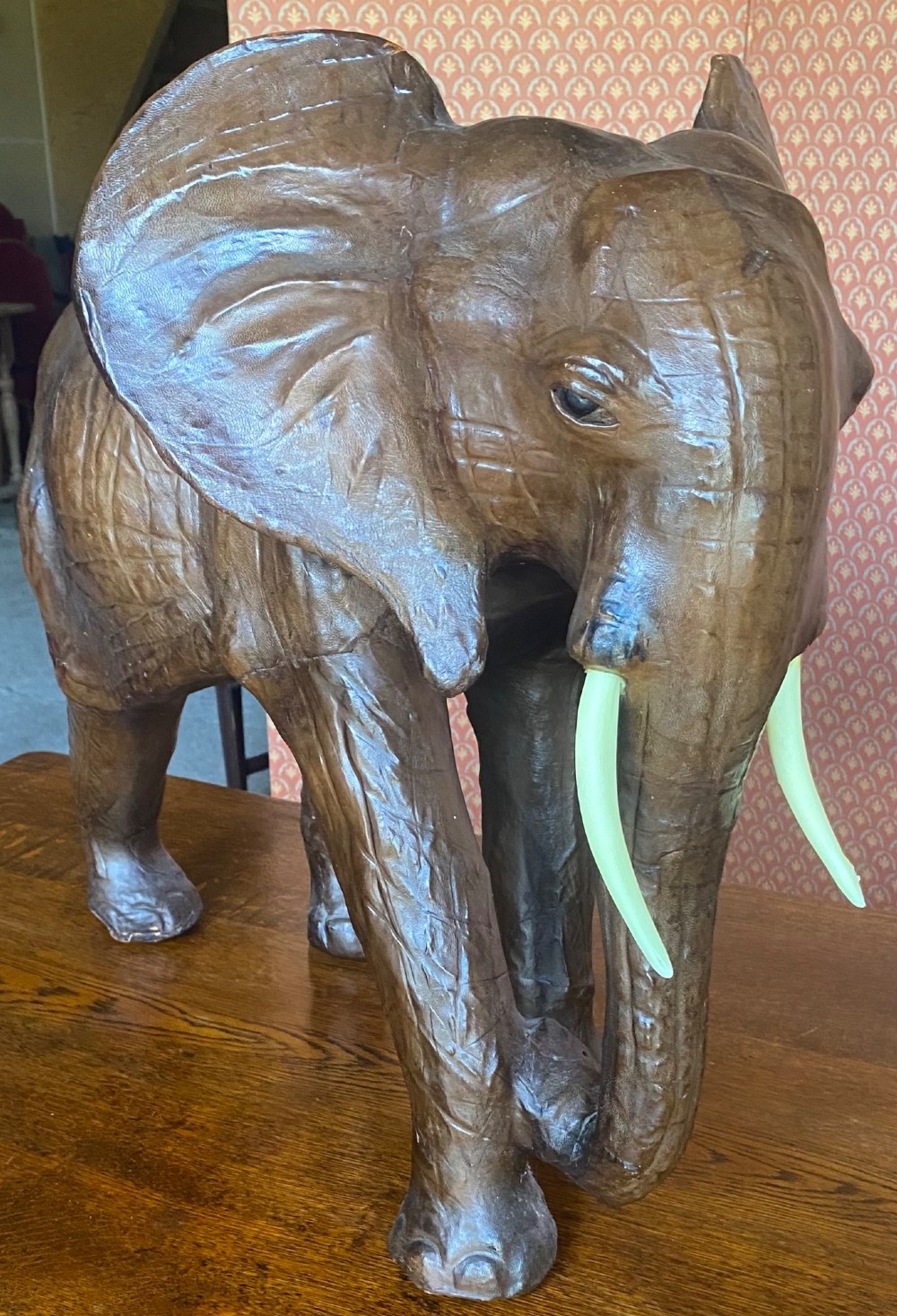 A pair of hand-crafted dark brown leather elephant statues standing with raised trunks and light-coloured tusks. View II