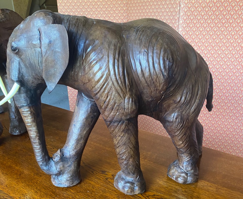 A pair of hand-crafted dark brown leather elephant statues standing with raised trunks and light-coloured tusks. View III