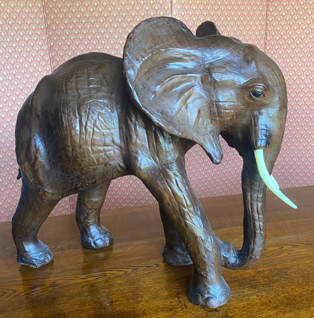 A pair of hand-crafted dark brown leather elephant statues standing with raised trunks and light-coloured tusks. View IV