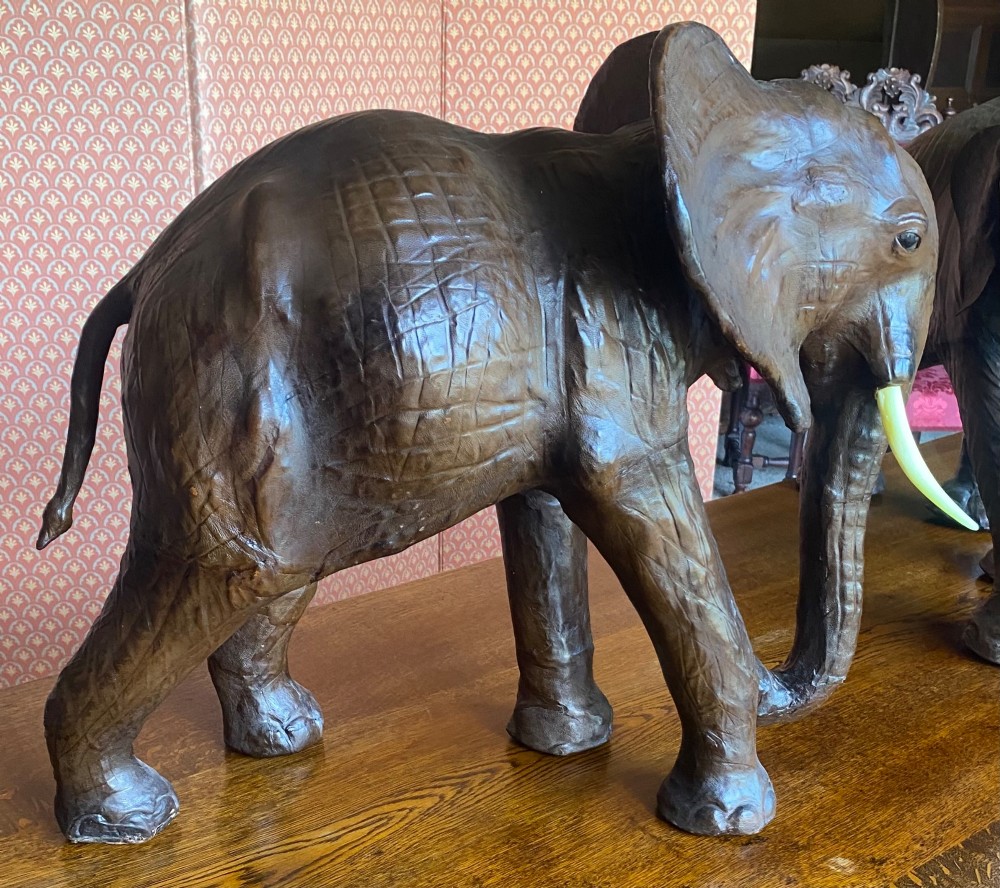 A pair of hand-crafted dark brown leather elephant statues standing with raised trunks and light-coloured tusks. View V