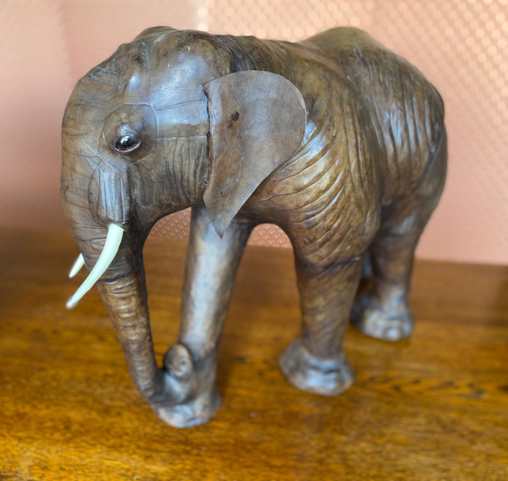 A pair of hand-crafted dark brown leather elephant statues standing with raised trunks and light-coloured tusks. View VI