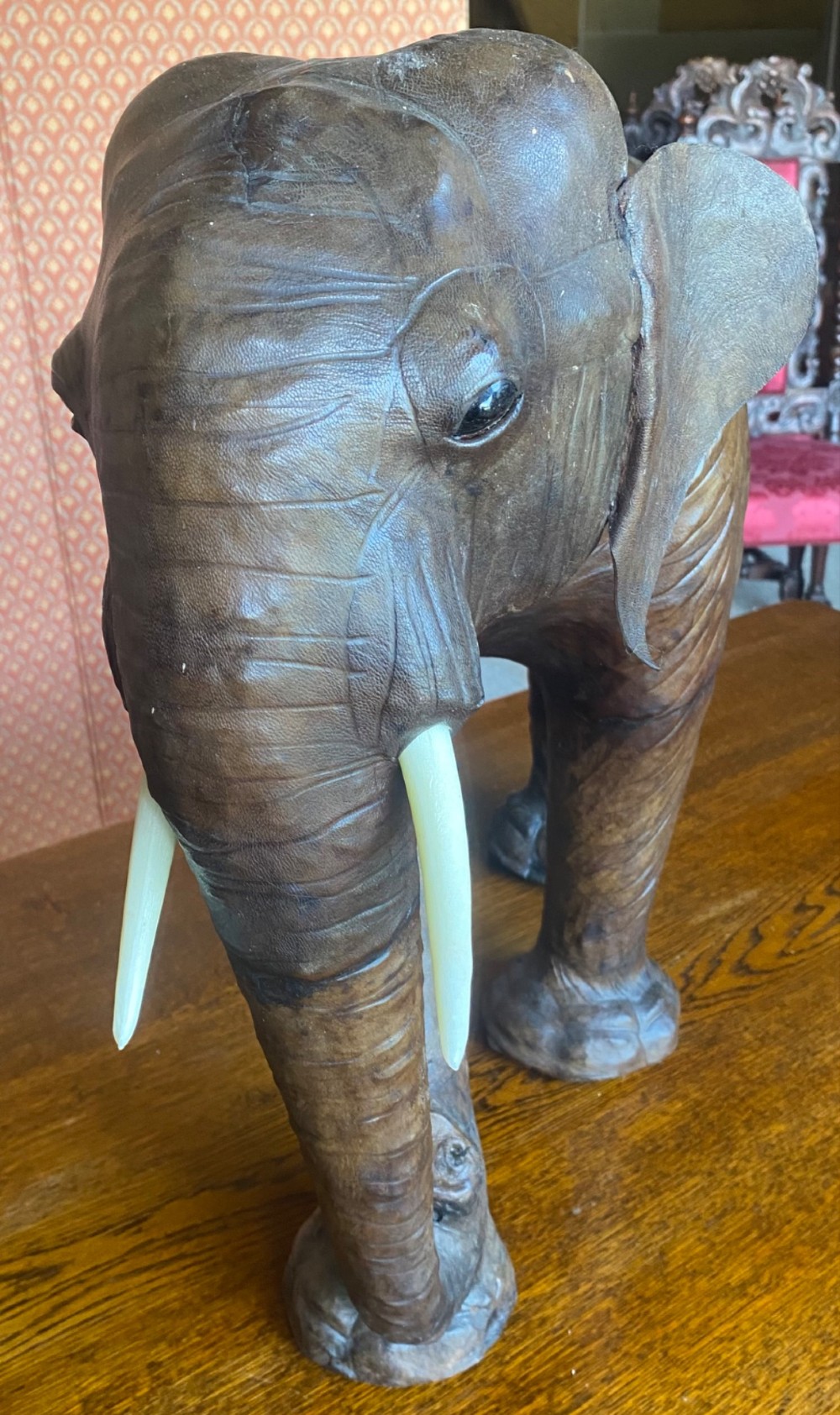 A pair of hand-crafted dark brown leather elephant statues standing with raised trunks and light-coloured tusks. View VII