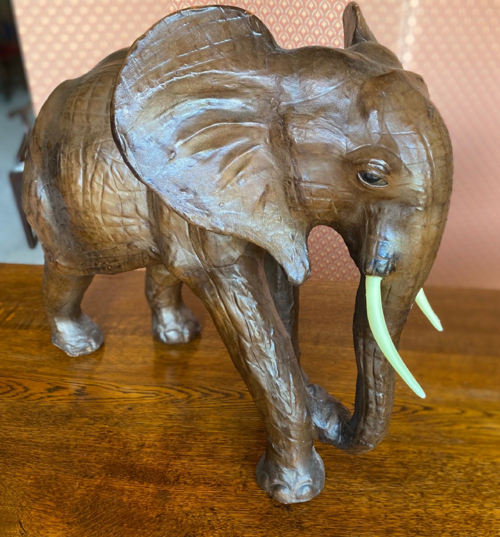 A pair of hand-crafted dark brown leather elephant statues standing with raised trunks and light-coloured tusks. View IX