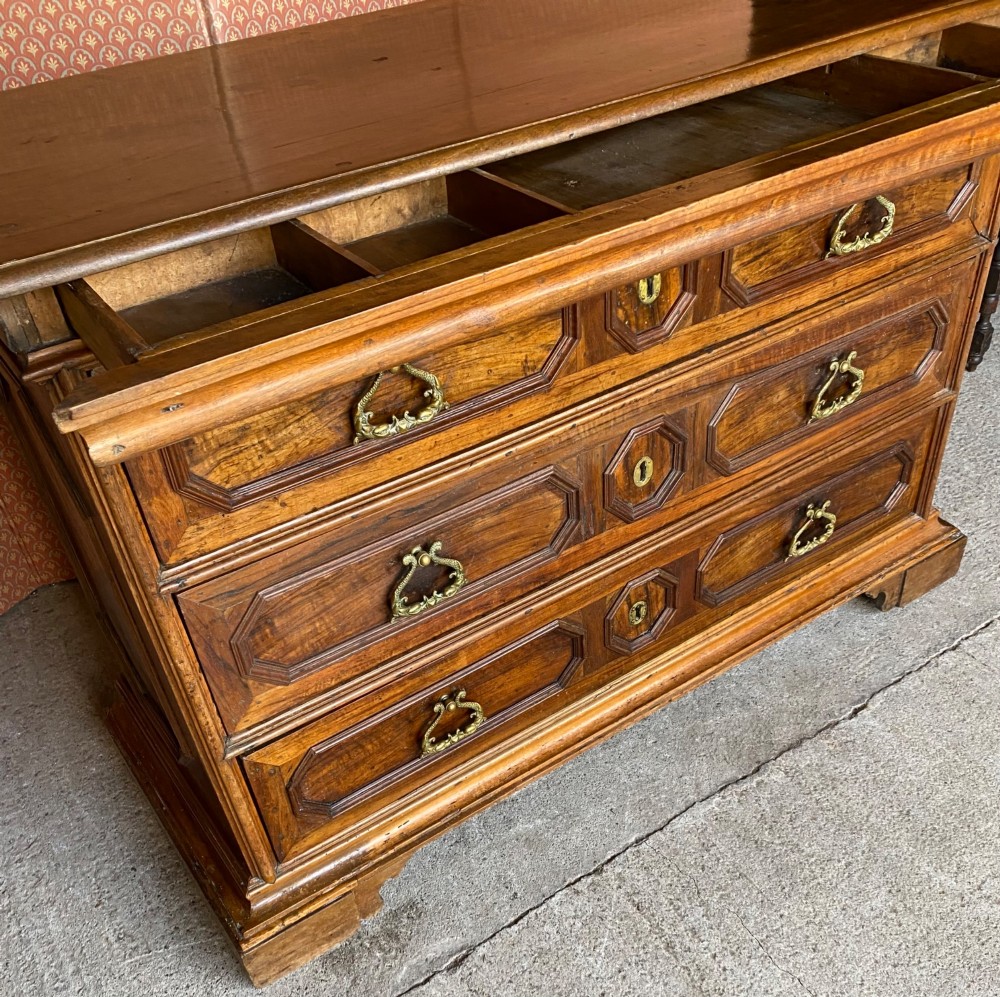An 18th-century Italian walnut chest of drawers featuring geometric panel mouldings, brass drop handles, and bracket feet. View II