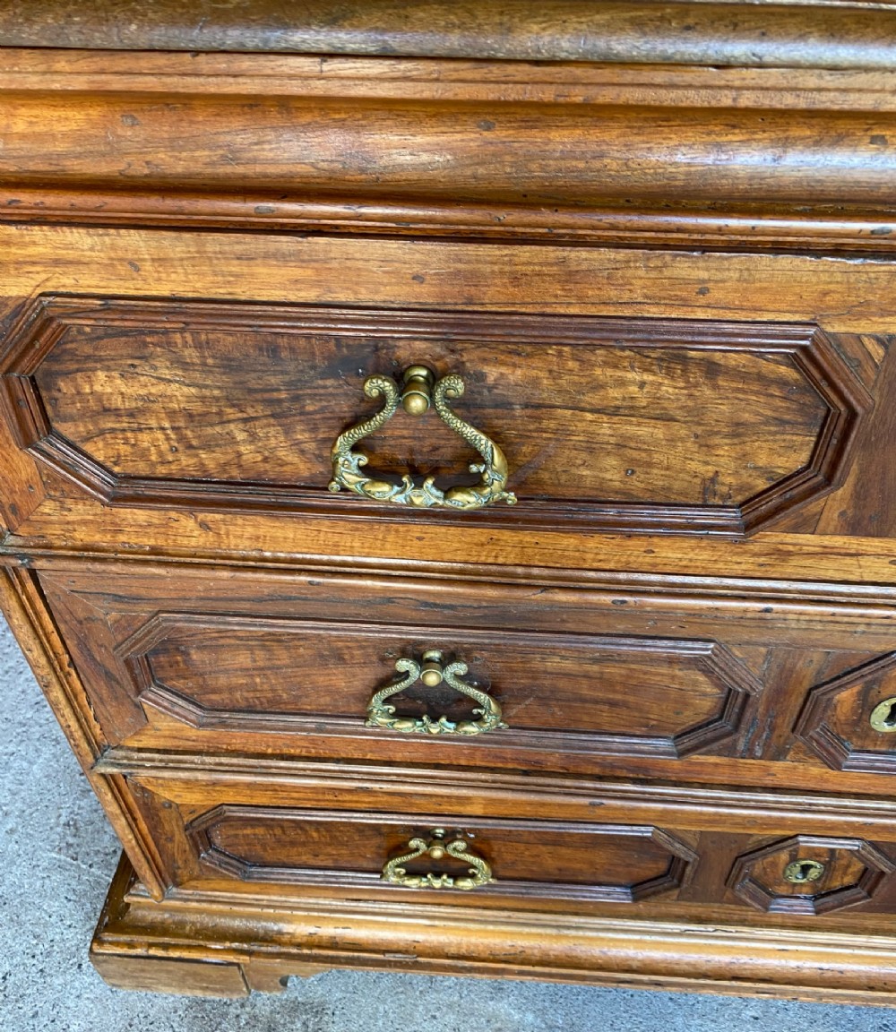 An 18th-century Italian walnut chest of drawers featuring geometric panel mouldings, brass drop handles, and bracket feet. View III