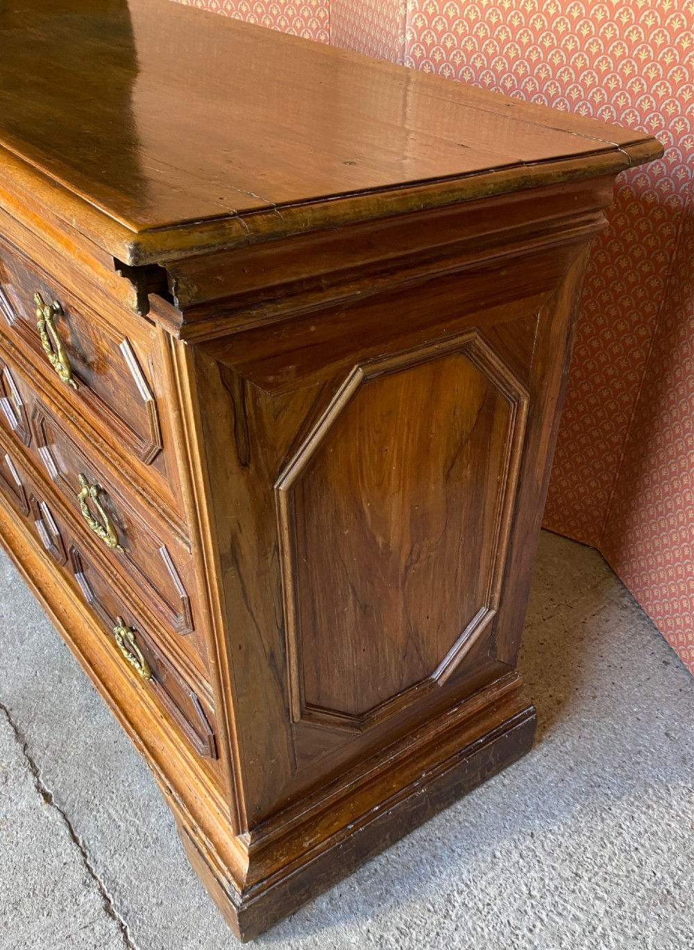 An 18th-century Italian walnut chest of drawers featuring geometric panel mouldings, brass drop handles, and bracket feet. View IV