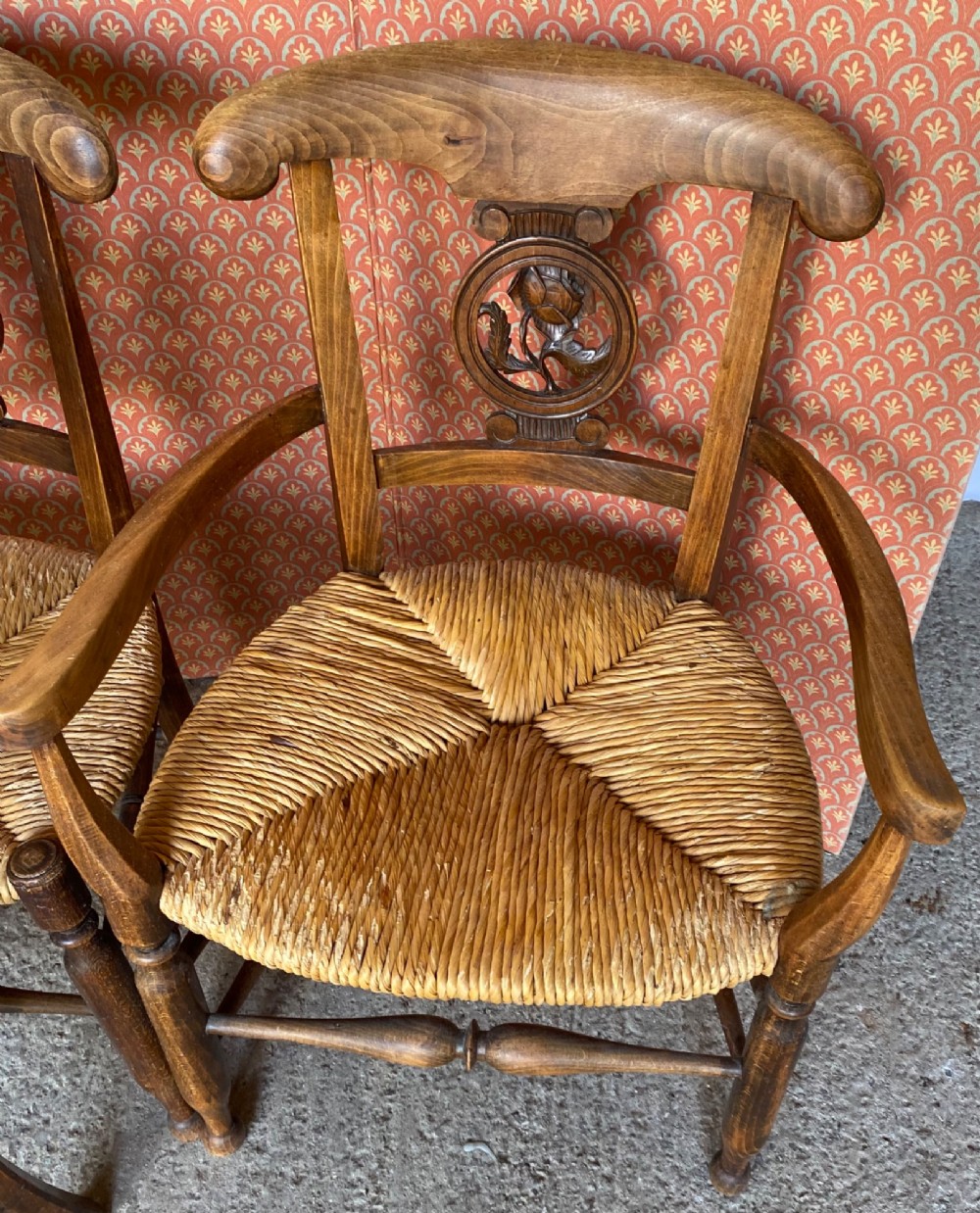 A set of six French country wooden dining chairs featuring hand-woven rush seats, turned legs, and carved floral roundels on the backrests. View II