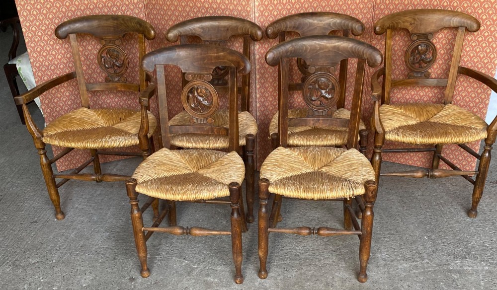 A set of six French country wooden dining chairs featuring hand-woven rush seats, turned legs, and carved floral roundels on the backrests. View III