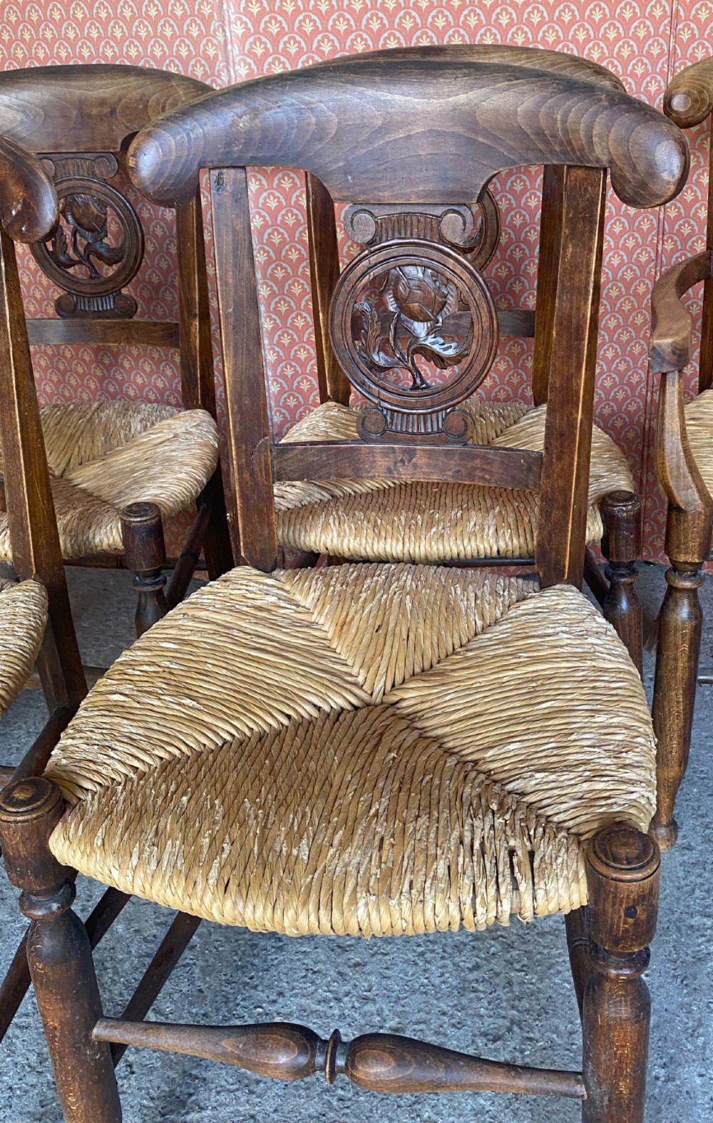 A set of six French country wooden dining chairs featuring hand-woven rush seats, turned legs, and carved floral roundels on the backrests. View IV