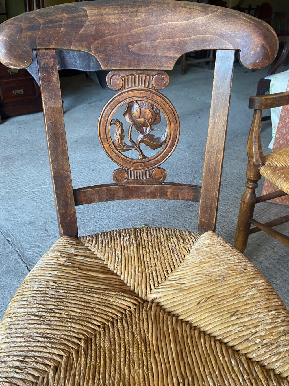 A set of six French country wooden dining chairs featuring hand-woven rush seats, turned legs, and carved floral roundels on the backrests. View V