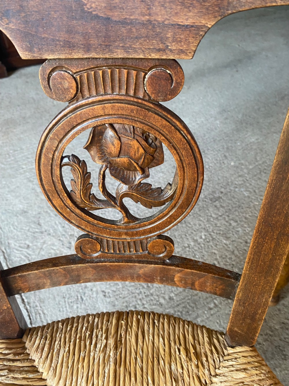 A set of six French country wooden dining chairs featuring hand-woven rush seats, turned legs, and carved floral roundels on the backrests. View VI