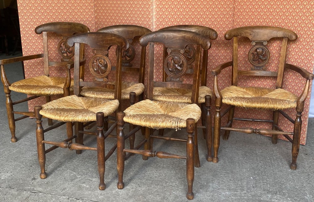 A set of six French country wooden dining chairs featuring hand-woven rush seats, turned legs, and carved floral roundels on the backrests. View VII