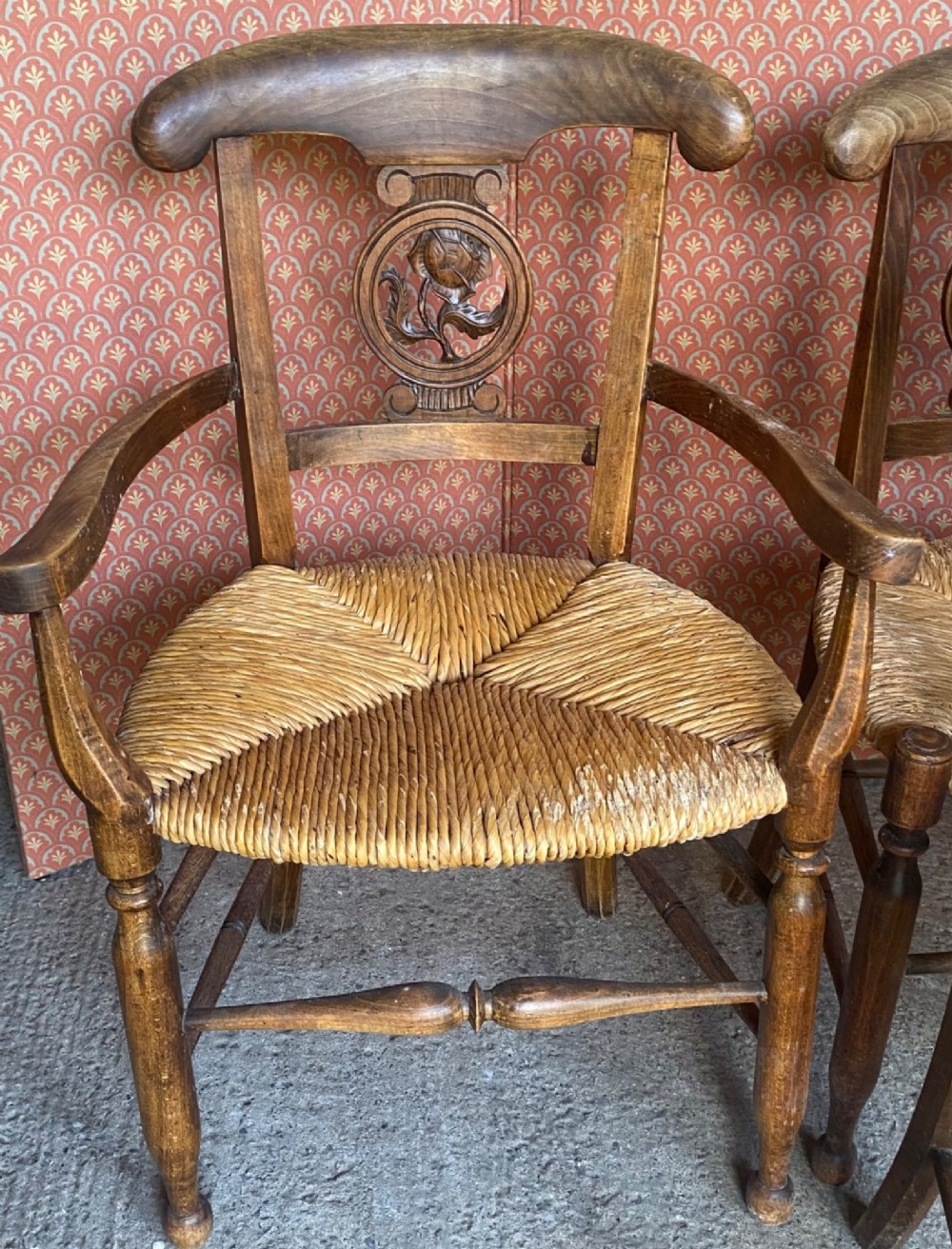 A set of six French country wooden dining chairs featuring hand-woven rush seats, turned legs, and carved floral roundels on the backrests. View VIII
