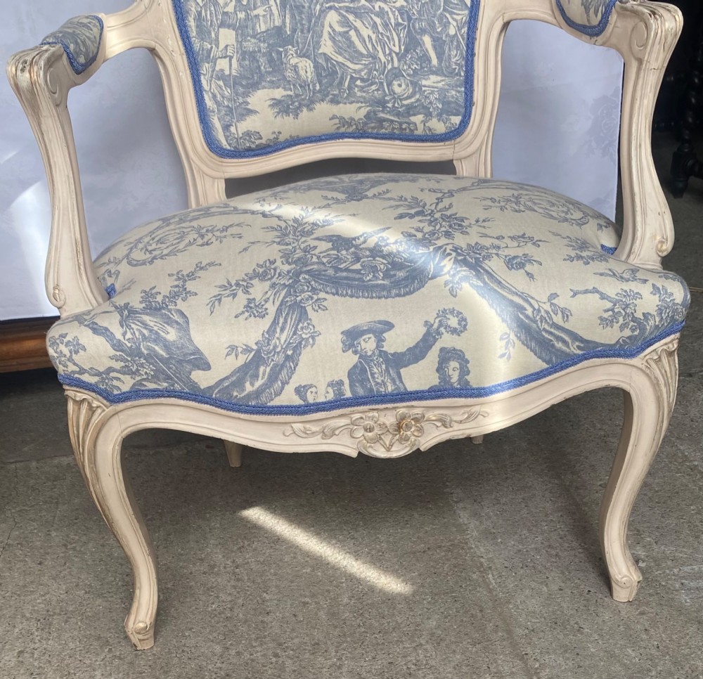 A pair of 19th-century French salon armchairs with off-white painted wooden frames, cabriole legs, and blue pastoral Toile de Jouy pattern upholstery. View II
