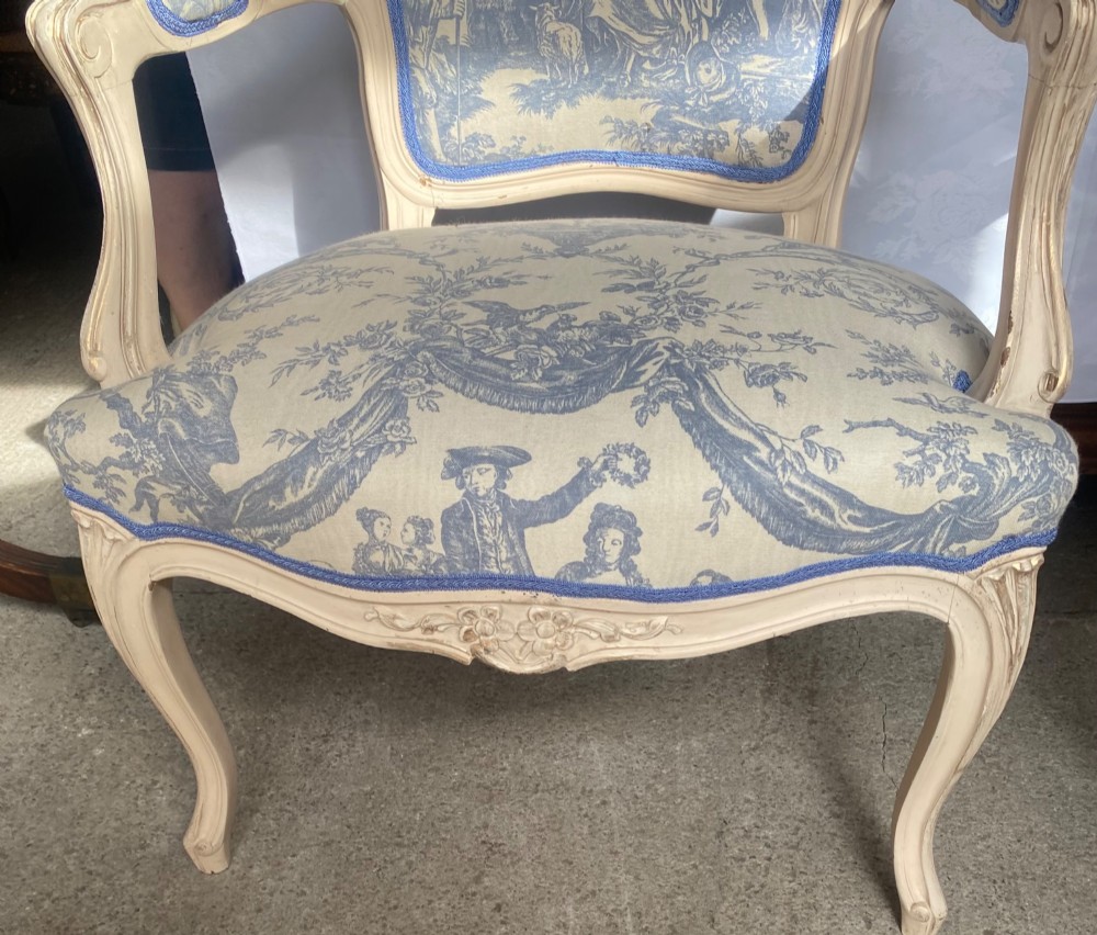 A pair of 19th-century French salon armchairs with off-white painted wooden frames, cabriole legs, and blue pastoral Toile de Jouy pattern upholstery. View III