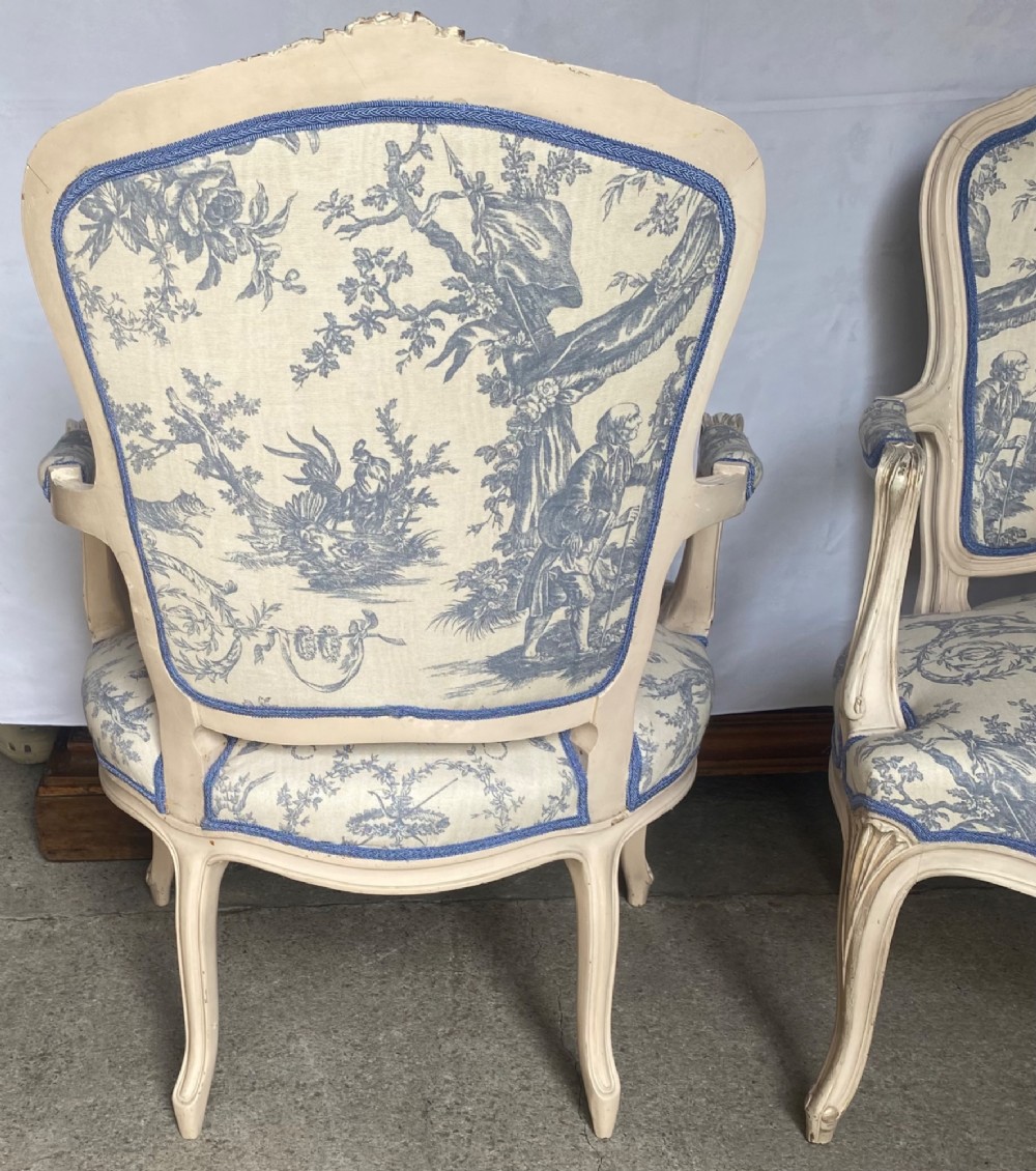 A pair of 19th-century French salon armchairs with off-white painted wooden frames, cabriole legs, and blue pastoral Toile de Jouy pattern upholstery. View IV